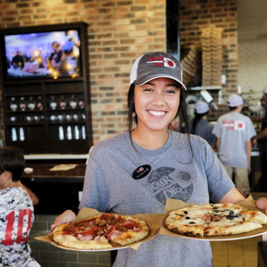 your pie pizza restaurant franchise emplyee holding two pizzas
