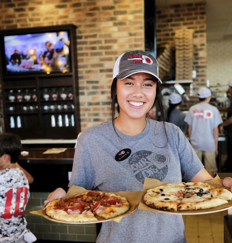 your pie pizza restaurant franchise emplyee holding two pizzas