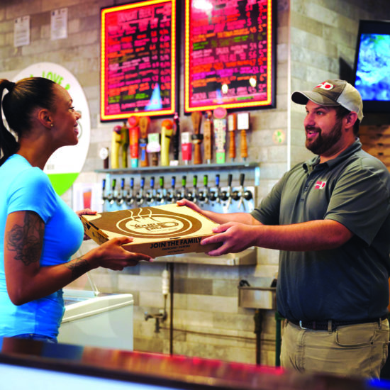 your pie pizza restaurant franchise employee handing pizza to customer